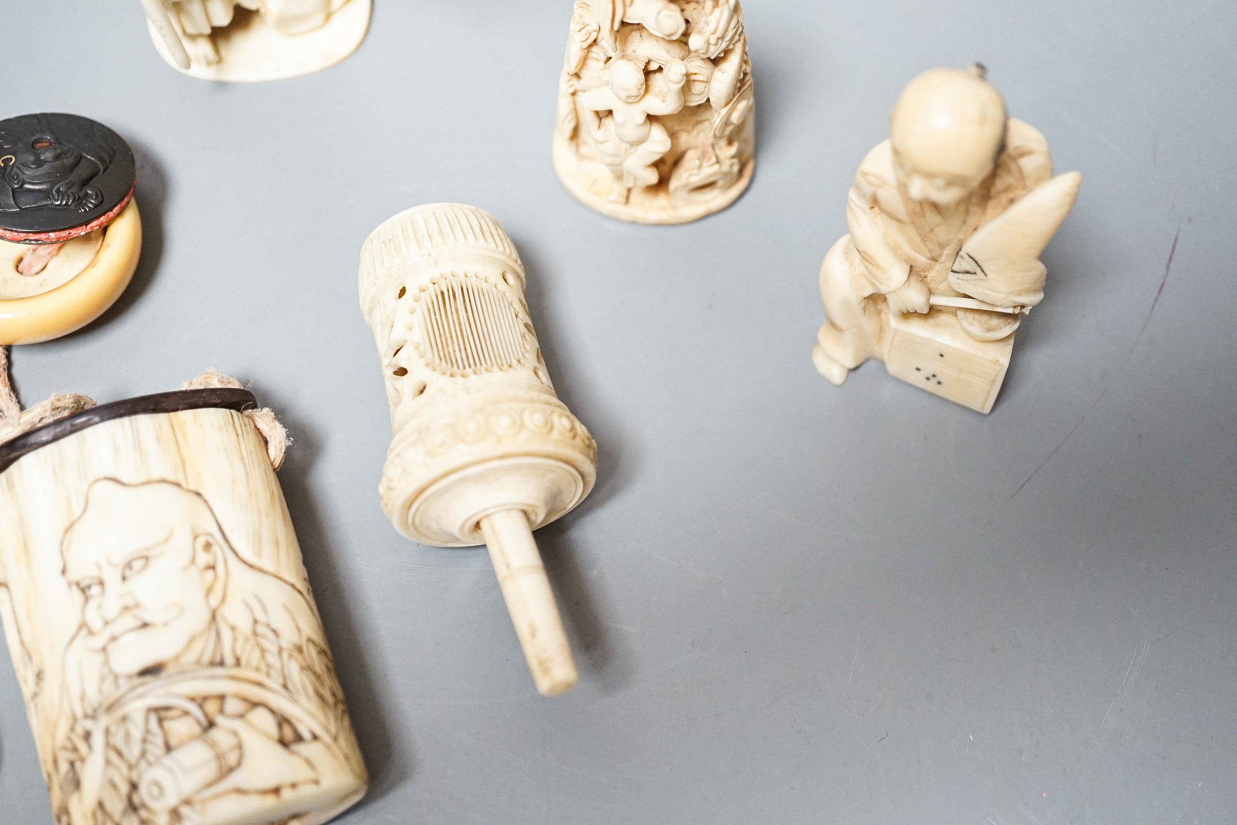 Three Japanese Ivory figures of men, a similar bezique marker, a Japanese staghorn single section inro with ivory manju, a Chinese ivory carving and a bone needlework container